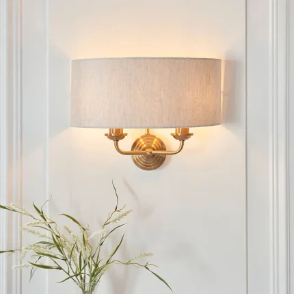 Wall light in aged brass finish with natural linen fabric shade