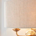 Wall light in aged brass finish with natural linen fabric shade