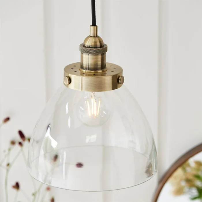 Single pendant light in antique brass finish with clear glass shade