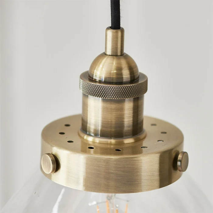 Single pendant light in antique brass finish with clear glass shade