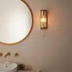 Bathroom wall light in brushed gold finish with clear glass shade